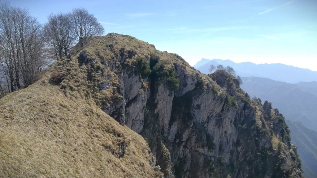 Dal costone roccioso spunta la piccola croce di vetta